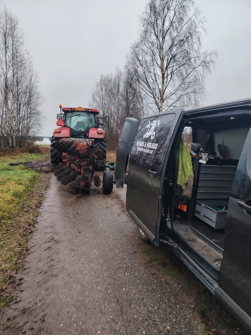 Huoltoauto traktorin ja auran vieressä pellon laidalla